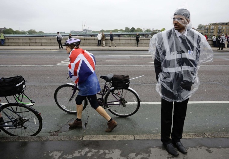 Image: File photo of  a guard using a plastic jacket to protect himself from rain on Putney Bridge in London