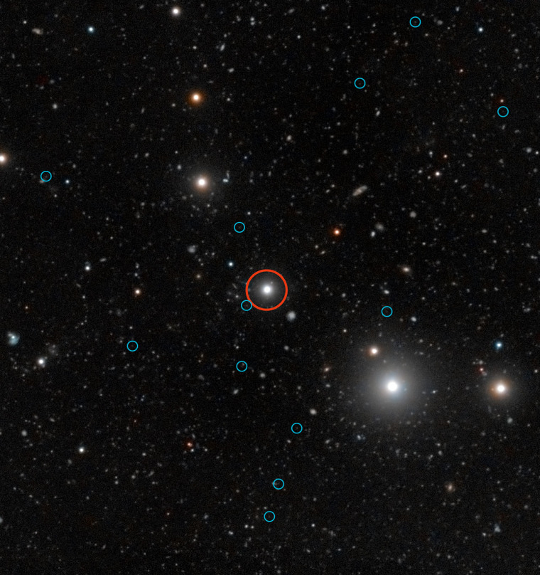 This deep image released on Wednesday shows the region of the sky around the quasar HE0109-3518. The quasar is labelled with a red circle near the center of the image. The faint images of the glow from 12 "dark galaxies" are labelled with blue circles.
