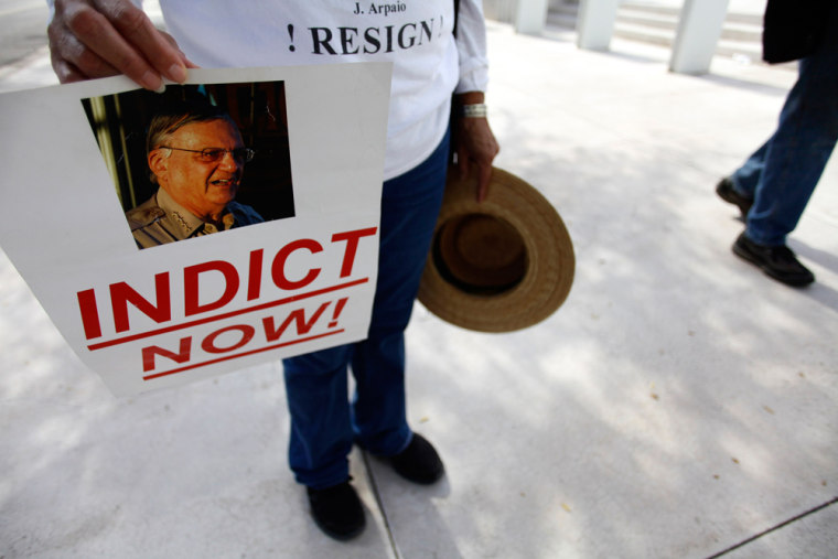 Image: A protester holds a sign with a picture of Maricopa County Sheriff Joe Arpaio outside the Sandra Day O'Connor United States Courthouse in Phoenix