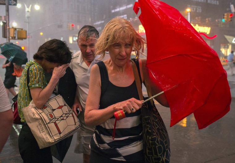 Image: Commuters dodge high wind and heavy rain during a thunderstorm in midtown Manhattan