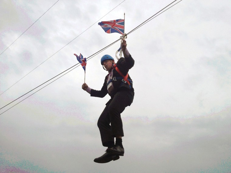 Image: London Mayor Boris Johnson dangles in the air after getting stranded on a zip wire during Olympics party at Victoria Park