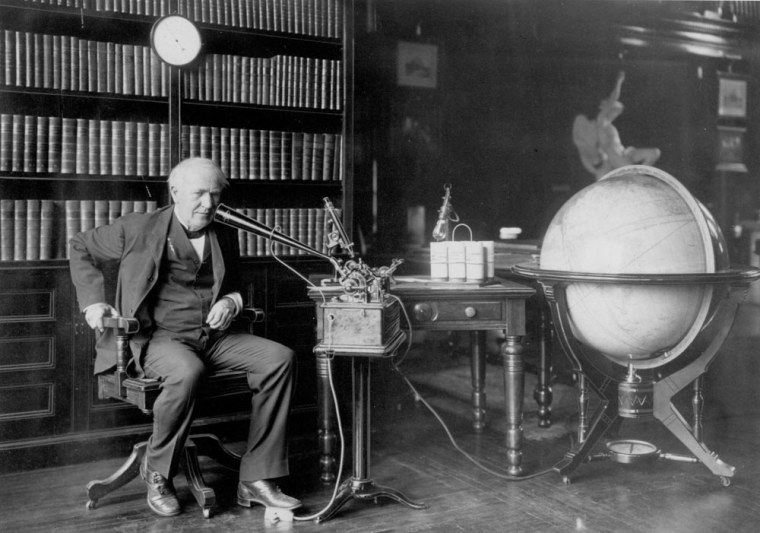 Thomas Edison is shown dictating to an Ediphone in his library.