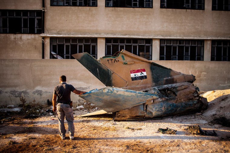 Image: A Free Syrian Army fighter examines the tail section of a downed Syrian Air Force MiG-21.