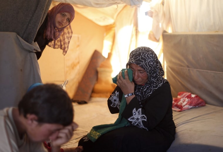 Image: A woman who fled her southern restive border town of Daraa, Syria with her family in July, wipes her eyes as she speaks during an interview at the Zaatari Refugee Camp.