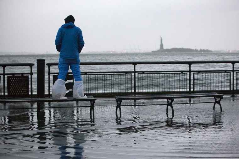 Image: A man watches the rising tides in Battery Park as Hurricane Sandy makes its approach in New York