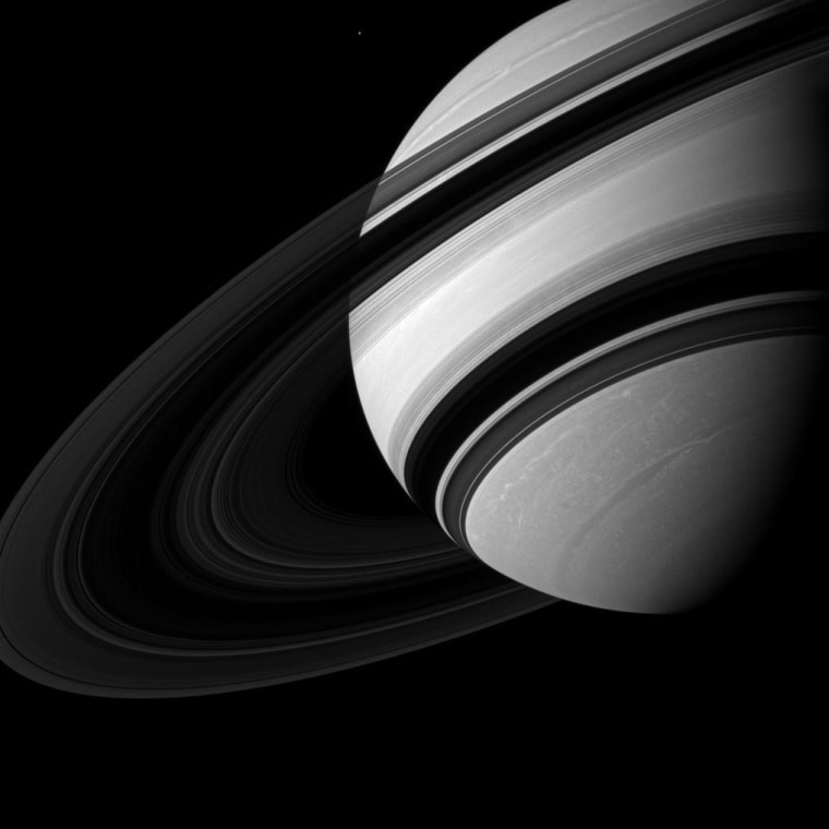 Saturn's moon Mimas appears near Saturn, dwarfed by its parent planet in this image. Mimas (246 miles, or 396 kilometers across) appears tiny compared to the storms clearly visible in far northern and southern hemispheres of Saturn. The image was taken with the Cassini spacecraft wide-angle camera on Aug. 20.