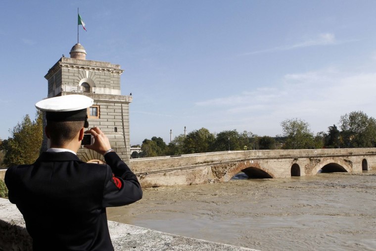 Image: Coast Guard officer takes a photo of the Milvio Bridge over the Tiber river flows in Rome