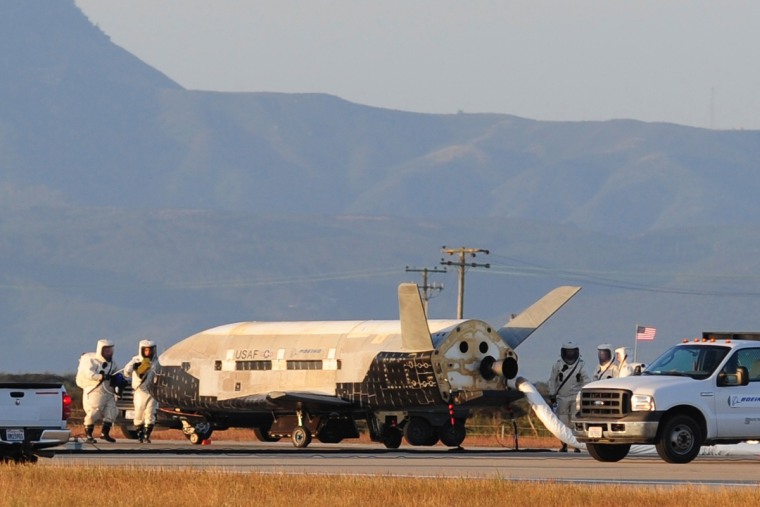 Technicians inspect the military X37-B space plane after its June 2012 landing, which completed the vehicle's second trip to orbit.
