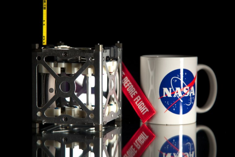 NASA's novel Phonesat 1.0 satellite is seen next to a coffee mug for size comparison. A trio of CubeSats make up the innovative PhoneSat Project to be launched in 2013.