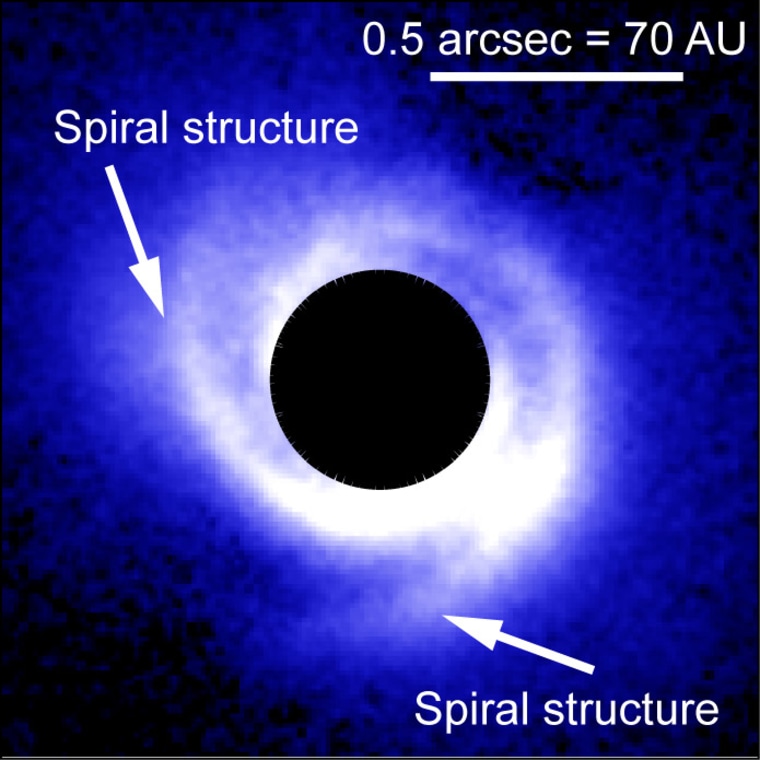An image of the disk around SAO 206462 captured with HiCIAO. A coronagraph blocks the direct light of the central star, which appears as the black, circular area in the image. Arrows show the two arms of the spiral structure around the star.