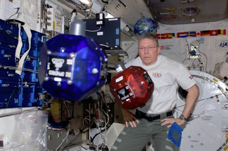NASA astronaut Mike Fossum operates small, autonomous satellites aboard the International Space Station in November 2011. Every year, high school students compete to submit computer code to run in the satellites, called SPHERES.