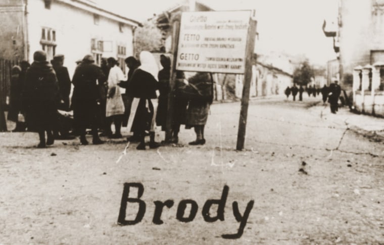 A group of Jewish women at the entrance to the Brody ghetto in Eastern Galicia, 1942. The sign is written in German, Ukrainian and Polish. 