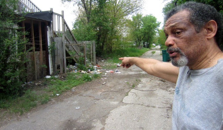 Arthur Joe points to trash spilling into the alley behind his house from abandoned properties in Gary.