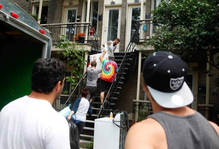 Image: Two movers wait their turn for the stairs as Hugo McMahon and his friends move things into his new apartment in Montreal.