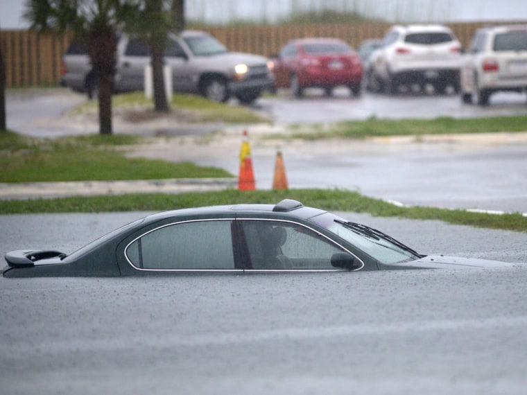 Image: An empty car is submerged in a flooded area of the parking lot of The Boardwalk on Okaloosa Island, Fla.