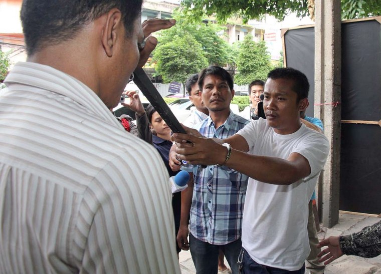 Image: Chidchai Utmacha, right, a Thai taxi driver shows how he stabbed an American passenger,