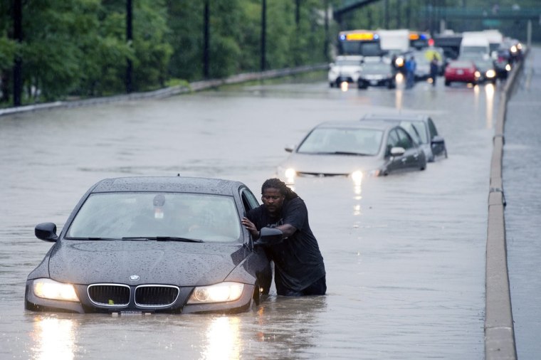 Image: A tow truck driver floats a car out of the Don Valley Parkway in Toronto