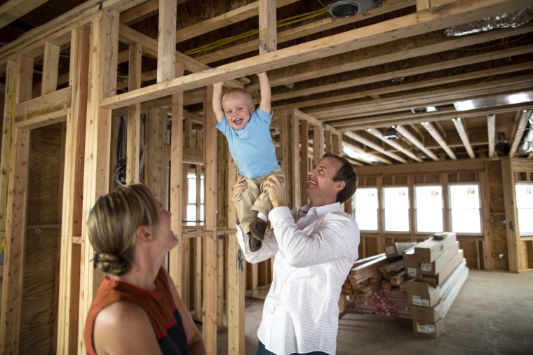 Image: chael and Elizabeth Carlson, with their son Michael Jr., visit their new home under construction, which they hope to be able to move into by Christmas.