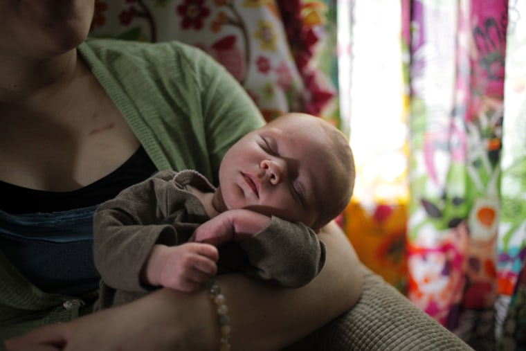 Image: Lisa Bender, who is undergoing treatment for breast cancer, holds her newborn baby daughter Alice in their home in Minneapolis, Minn. on April 1.