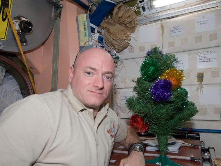 NASA astronaut Scott Kelly, commander of Expedition 26 aboard the International Space Station, poses for a holiday photo near the station's miniature Christmas tree in 2010.