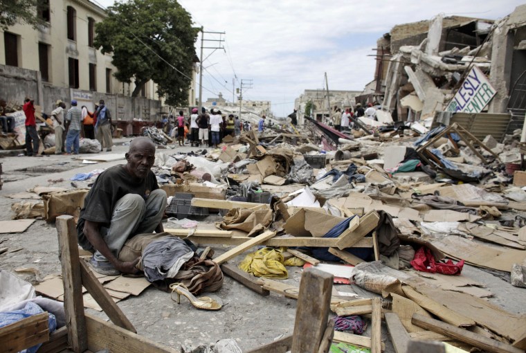 Image: A resident sits at a destroyed area after a major earthquake hit the capital Port-au-Prince