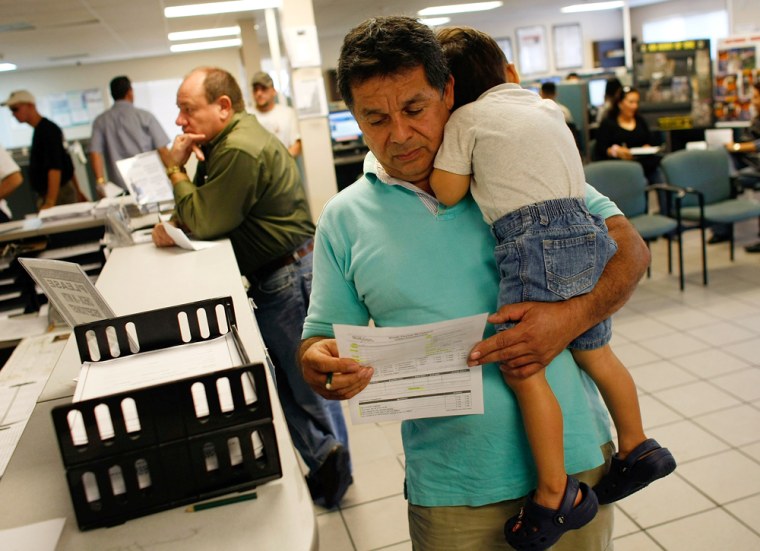 Image: Juan Carlos Rojas holds his 2 year old son, Juan Pablo Rojas, as he prepares to fill out paperwork for unemployment benefits in Miami, Fla.