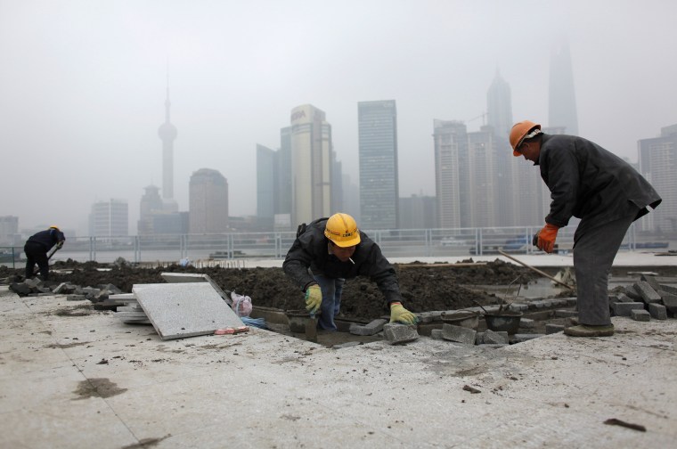 Image: Migrant labourers work at a construction site near The Bund on the banks of the Huangpu River in Shanghai