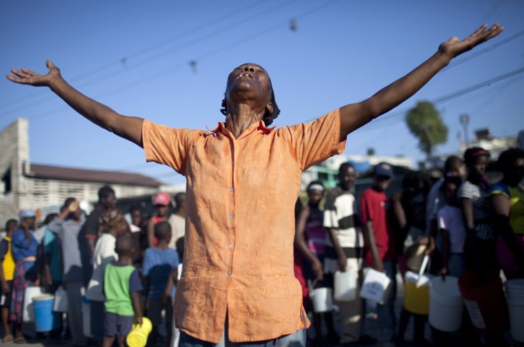 Image: A woman prays and sings in a street in Port-au-Prince