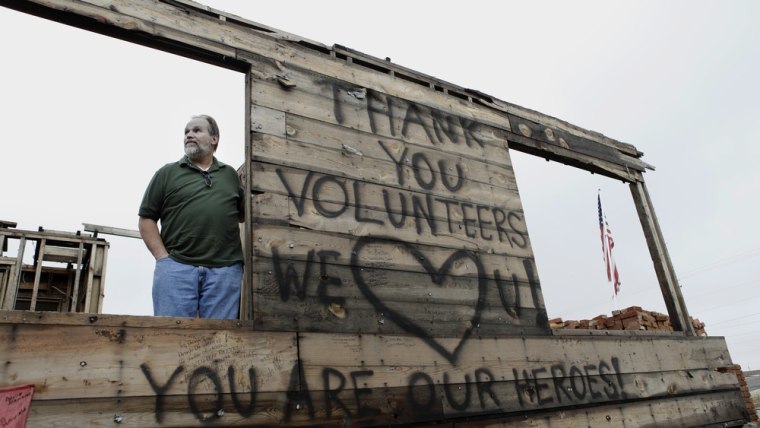 Image: Tim Bartow at his damaged home filled with messages written by volunteers.