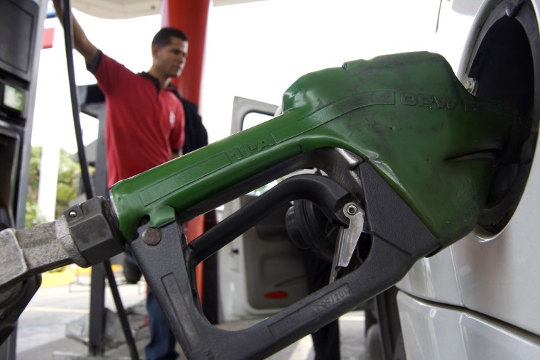 Image: An employee fuels up a car in a gas station in Caracas