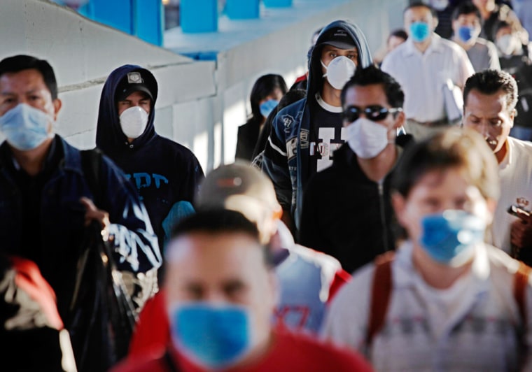 Image:  Passengers wearing face masks as a precaution against swine flu walk inside a metro station in Mexico City