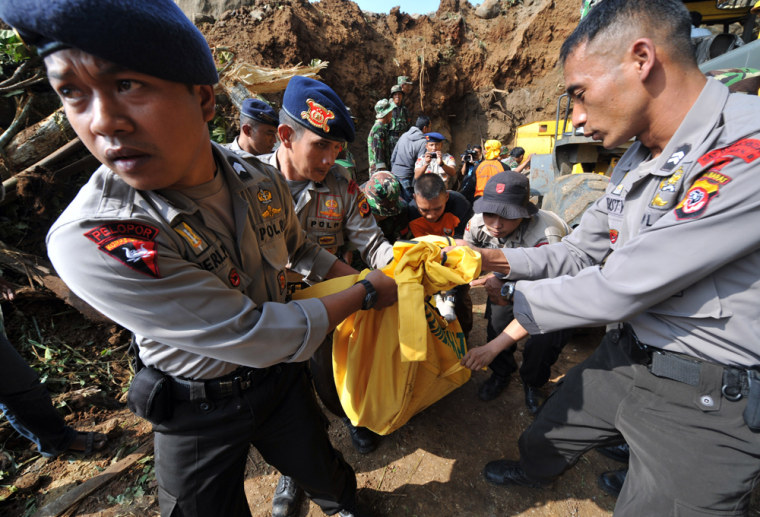 Image: Indonesian police carry a dead body during an evacuation at Cikangkareng village in Cibinong