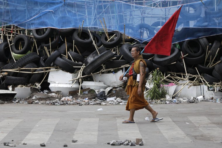 Image: Buddhist monk walks along the barricade, built with bamboo poles and tyres, in the Silom business district in Bangkok