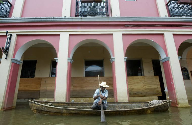 Image: A man waits on a canoe in flooded Tlacot