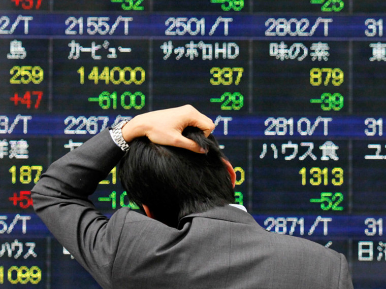 Image: A man reacts while looking at a stock price board in Tokyo Monday, March 14, 2011 as the Tokyo stock market plunged on its first business day after an earthquake and tsunami hit the country.