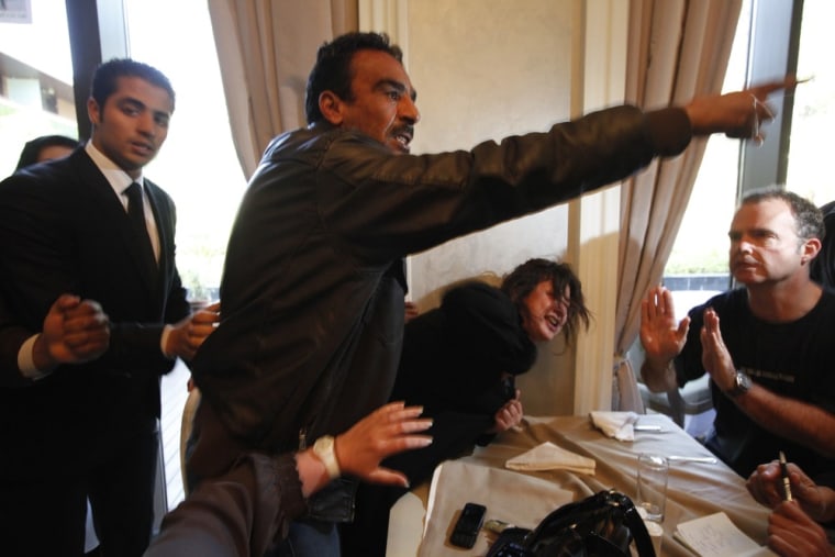 Image: A Libyan woman reacts as she is grabbed by a Libyan official preventing members of the foreign media from reaching her, at a hotel in Tripoli