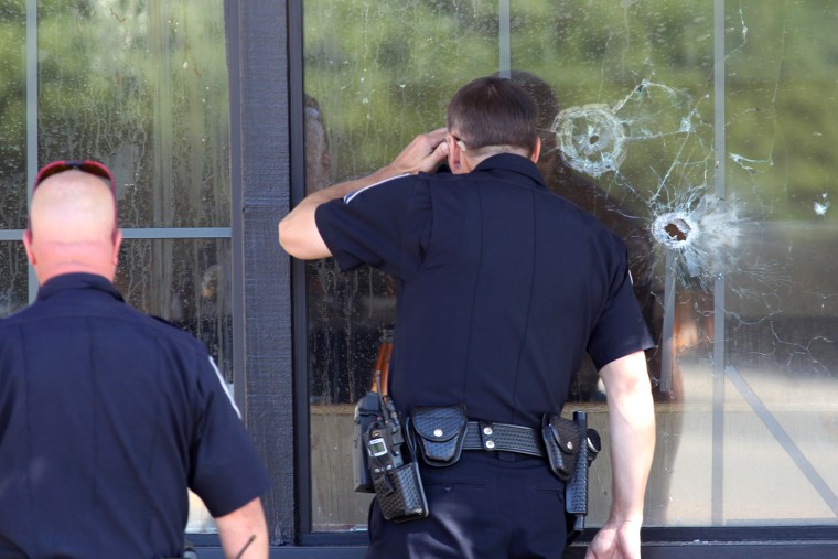 Image: Officers look through a bullet-damaged window of an IHOP restaurant