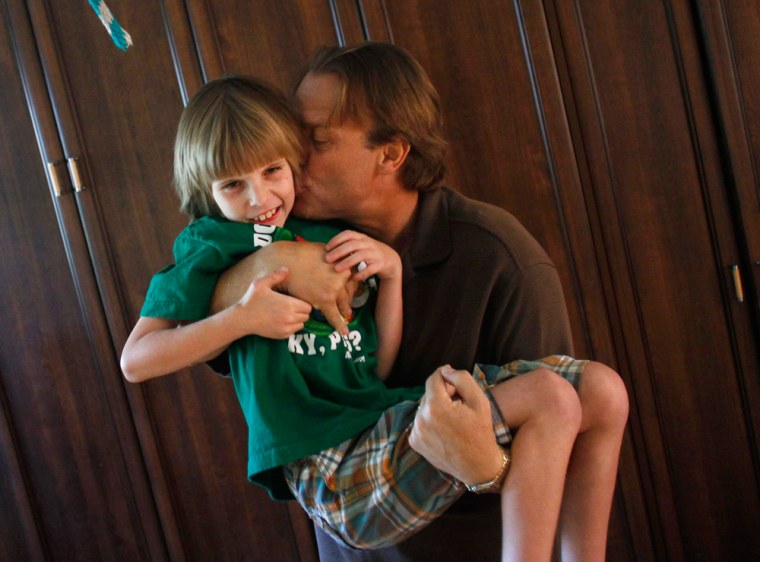Image: Nine-year-old Jack Balter receives a kiss from his father Neil as his sister Brianna looks on at their home in Scottsdale, Arizona, May 17, 2012