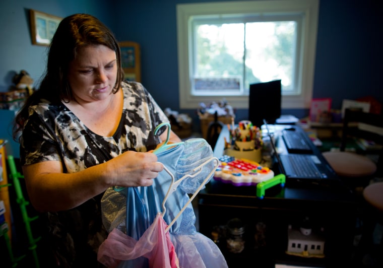 Image:  Mary Conti of Pittsburgh, PA., sorts through her daughters' princess dresses before listing them for sale on a consignment web site.