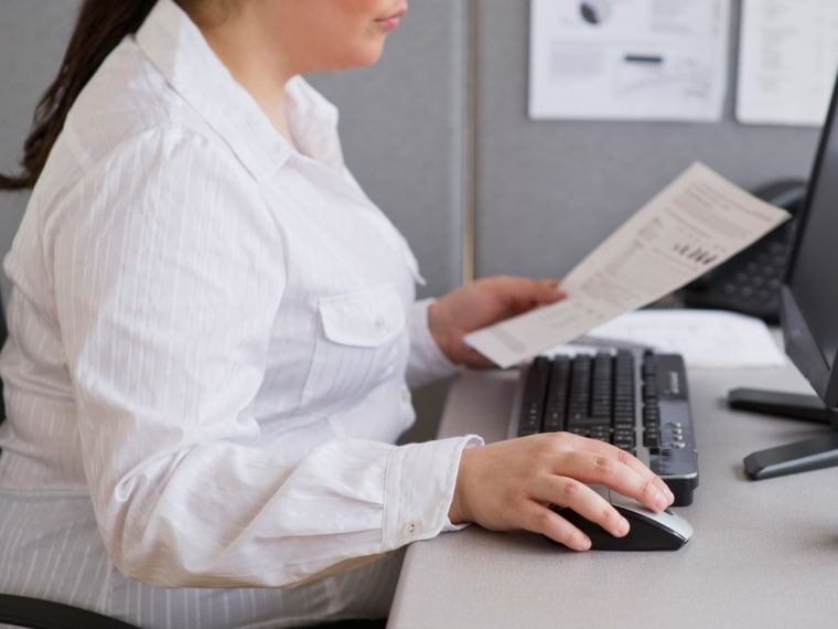 Businesswoman working on laptop in cubicle
