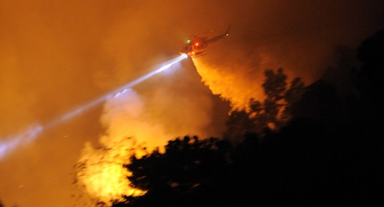 Image: A helicopter douses a wildfire in Calif.