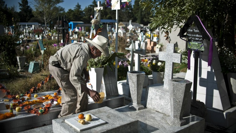 Image: A man cleans the grave of a relative at San Isidro cemetery in Mexico City,