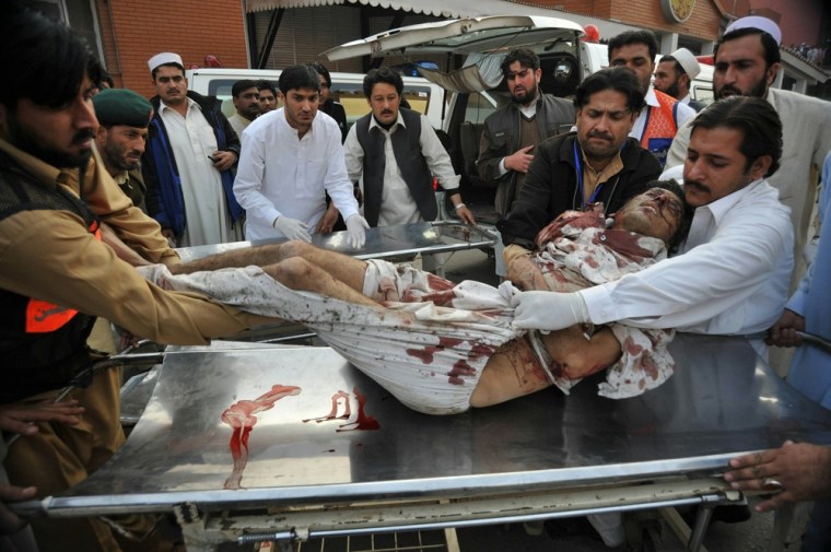 Image: Pakistanis help a wounded man at a hospi