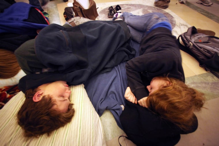 Image: Uinversity of Wisconsin sophomores Nick Crowley and Anna Wendland sleep in the rotunda of the Capitol in Madison, Wis.