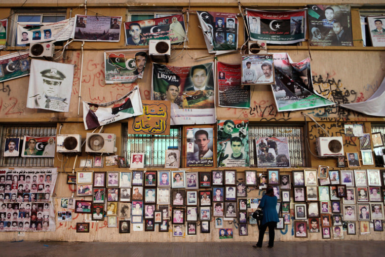 A woman looks at pictures of deceased rebel fighters, killed during the revolution, hanging on the wall of a court house, in Liberation Square in Benghazi on Sept. 10, 2011.