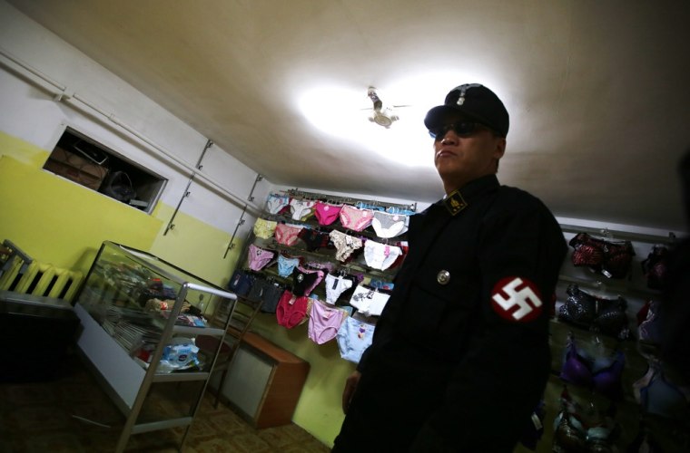 Image: Leader of Mongolian neo-Nazi group Tsagaan Khass walks through a lingerie store as he leaves the group's headquarters in Ulan Bator