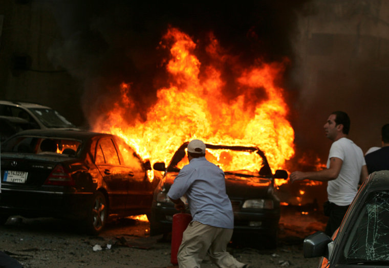 Image: Men try to extinguish fire from burning cars at the site of an explosion, in Beirut's southern suburbs