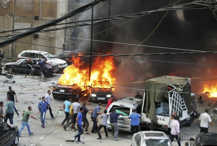 Image: Civil Defence members and residents gather at the site of an explosion in Beirut's southern suburbs