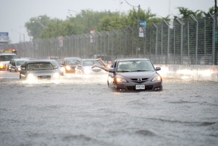 Image: A woman gets back in her car in flood water on Lakeshore West during a storm in Toronto.