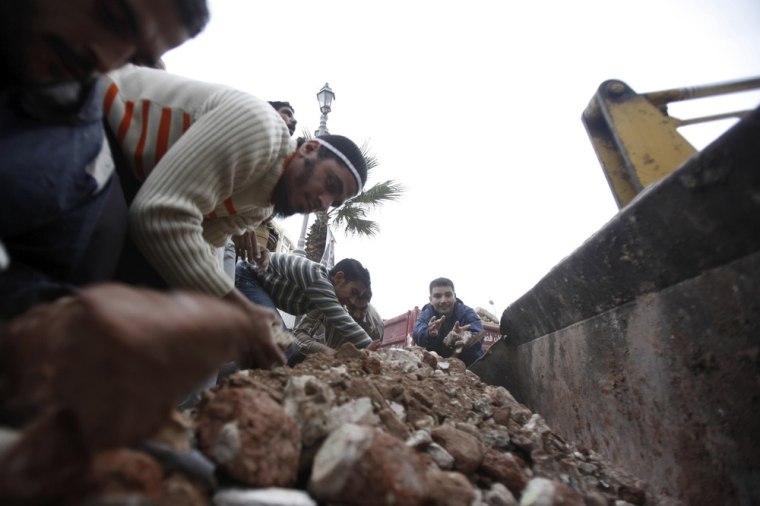 Image: Egyptian volunteers clean up garbage and rocks from the street near the Security Administrative building in Alexandria